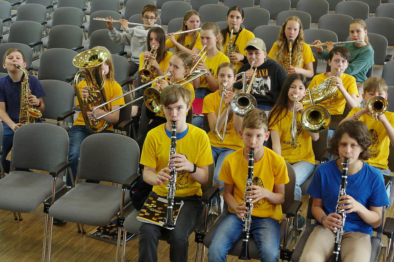 Schülerinnen und Schüler mit Instrumenten in gelben T-Shirts