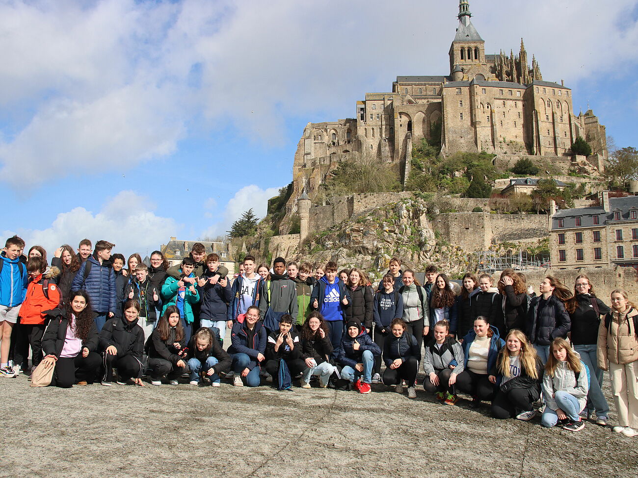 Schülerinnen und Schüler posieren für ein Gruppenfoto vor Le Mont-Saint-Michel